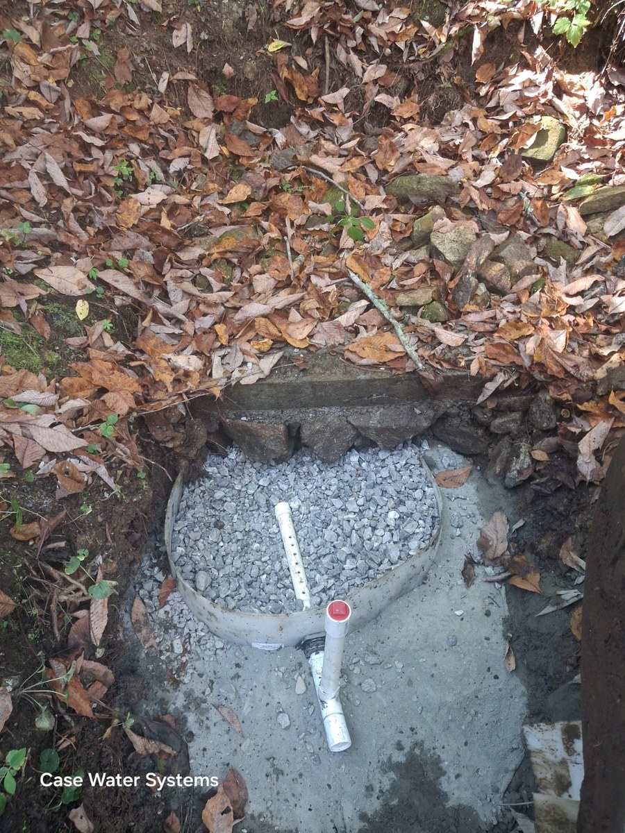 Spring collection area with gravel, concrete and pipes.